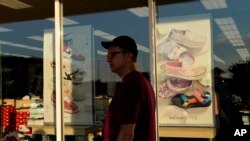 FILE - A shopper walks past a storefront window at an outlet mall in Rehoboth Beach, Del., June 4, 2022.