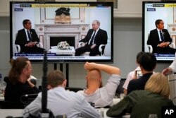 Wartawan menyaksikan pertemuan Presiden Rusia Vladimir Putin dan Presiden Indonesia Joko Widodo di Kremlin di Moskow, Rusia, melalui layar televisi, Kamis, 30 Juni 2022. (AP /Alexander Zemlanichenko, Pool)