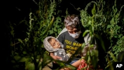 FILE - In this Aug. 18, 2021, photo, Afghan migrants sit in the countryside in Tatvan, in Bitlis province, eastern Turkey.