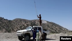 A Taliban member tries to get a communication signal on top of a vehicle in the quake-hit area of Wor Kali village in the Barmal district of Paktika province, Afghanistan, June 25, 2022. 