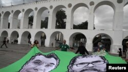 Sejumlah demonstran membentangkan spanduk bergambar jurnalis Inggris Dom Phillips dan tokoh masyarakat adat Brazil Bruno Pereira dalam aksi protes di Arcos da Lapa di Rio de Janeiro, Brazil, pada Juni 2022. (Foto: Reuters/Pilar Olivares)