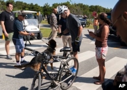 President Joe Biden communicates to his dog, Commander after greeting a crowd at Gordons Pond in Rehoboth Beach, Del., Saturday, June 18, 2022. Biden fell as he tried get off his bike to greet the crowd along the trail.