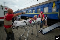 Paramedis mendorong seorang perempuan lansia di atas brankar ke dalam kereta medis yang dilengkapi peralatan khusus yang dioperasikan oleh Doctors Without Borders (MSF) untuk mengevakuasi pasien yang terluka dari daerah yang dilanda perang, di Pokrovsk, wilayah Donetsk, Ukraina, Rabu, 15 Juni 2022. (AP Photo/Efrem Lukatsky)