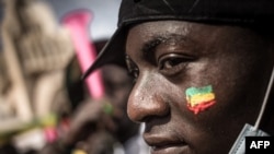 FILE: A demonstrator watches the crowd with a Malian flag painted on his cheek, during a mass demonstration in Bamako, on January 14, 2022, to protest against sanctions imposed on Mali and the Junta by the Economic Community of West African States (ECOWAS).