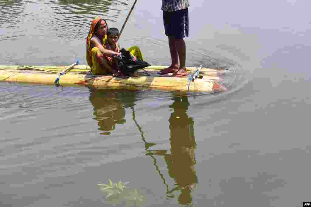 Villagers travel on a makeshift floating device in flood waters at Hatibhangi village in Morigaon district, in India&#39;s Assam state.