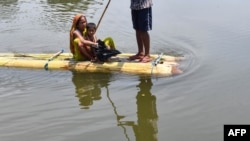 Villagers travel on a makeshift raft in flood waters at Hatibhangi village in Morigaon district, in India&#39;s Assam state.