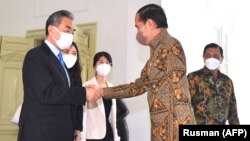 Presiden Jokowi berjabat tangan dengan Menteri Luar Negeri China Wang Yi di Istana Merdeka, Jakarta, 11 Juli 2022. (Foto: AFP/Rusman)