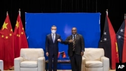 In this photo released by Xinhua News Agency, Papua New Guinea (PNG) Prime Minister James Marape at right bumps elbows with visiting Chinese Foreign Minister Wang Yi in Port Moresby, Papua New Guinea, Friday, June 3, 2022.