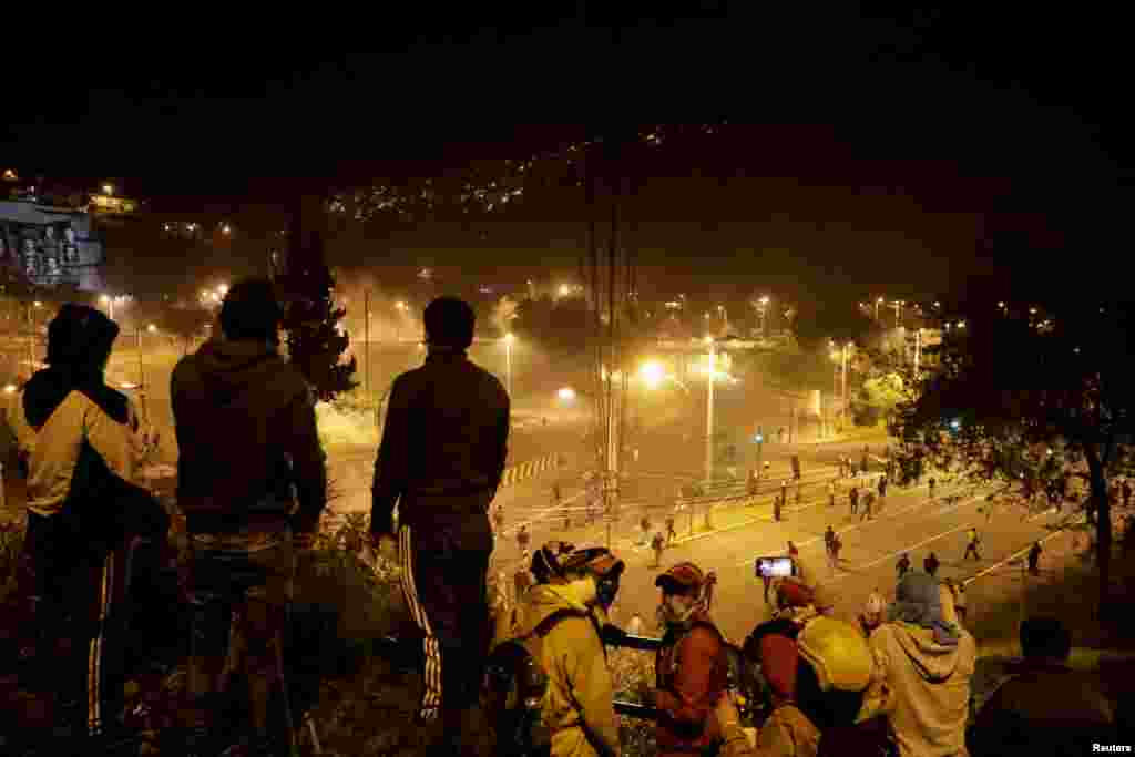 Un grupo de hombres miran a los manifestantes que se dispersan en una de las calles de Quito, Ecuador.&nbsp;