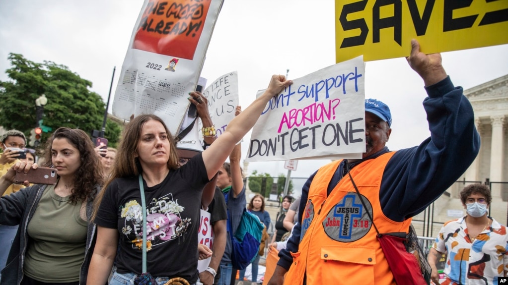 2022年5月14号，支持和反对妇女堕胎权利的美国民众聚集在美国最高法院外举行抗议活动。一名支持堕胎权利的女士试图用手里的标语牌遮盖她身旁一位反对堕胎的抗议人士手中的标语板。-照片来自美联社