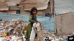 Seorang anak pengungsi asal Afghanistan tampak memilah milih sampah untuk mencari barang yang dapat didaur ulang agar ia dan keluarganya dapat bertahan hidup selama berada di Karachi, Pakistan. Foto diambil pada 19 Juni 2022. (Foto: AP/Fareed Khan) 