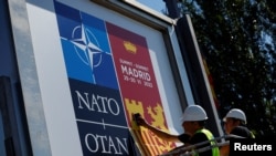 Workers paste posters announcing the NATO Summit outside the Madrid Fair in Madrid, June 27, 2022.