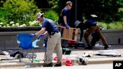 FILE - FBI members clean a fatal shooting site in the U.S. state of Illinois, July 5, 2022. The Supreme Court said Wednesday that Illinois can, for now, keep a new law — largely inspired by the shooting — barring the sale of some semiautomatic guns and large-capacity magazines.