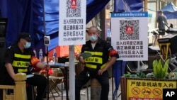 北京街头两名保安把守需要扫健康码和社区出入证方能出入的社区入口。（2022年6月20日）