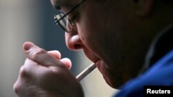 FILE - A smoker lights a cigarette in downtown Toronto. "Poison in every puff” is the warning the Canadian government is planning on having on each cigarette sold in the country. 
