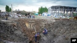 Police members inspect a crater caused by a Russian rocket attack in Pokrovsk, Donetsk region, Ukraine, June 15, 2022.