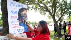 Cynthia Moreno, 32, menempelkan flyer di seberang jalan dari kantor Imigrasi dan Bea Cukai AS pada 15 Juni 2022, di Miramar, Amerika. (Foto: AP)