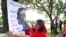 Cynthia Moreno, 32, menempelkan flyer di seberang jalan dari kantor Imigrasi dan Bea Cukai AS pada 15 Juni 2022, di Miramar, Amerika. (Foto: AP)