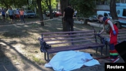 A medical worker stands near a body of a man, following Russian shelling in Kharkiv, Ukraine, June 27, 2022. 