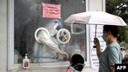 Un trabajador de la salud toma una muestra de hisopo de una niña para analizar el coronavirus COVID-19 en una estación de prueba de ácido nucleico en Beijing, China, el 22 de junio de 2022.