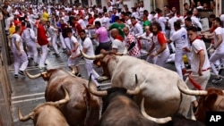 Orang-orang berlarian di jalanan pada hari pertama adu banteng dan sapi jantan di Festival San Fermin, Pamplona, Spanyol utara, Kamis, 7 Juli 2022. (AP/Alvaro Barrientos)