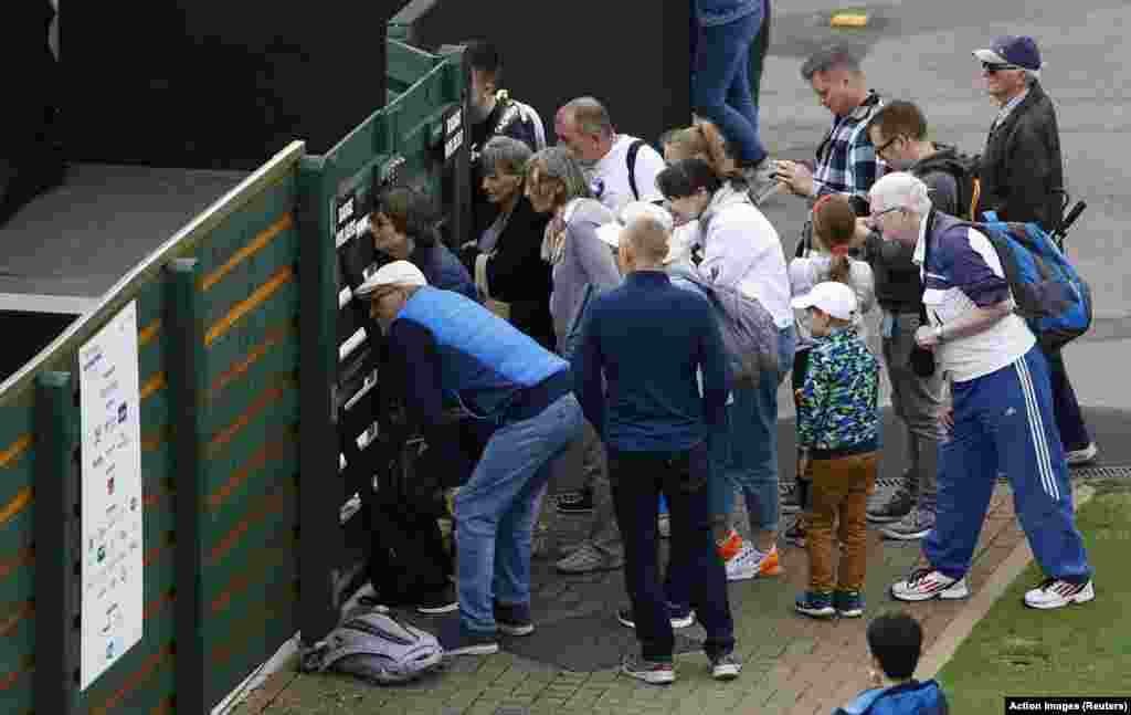 Fans look through the fence during the qualifying match of the Eastbourne international tennis tournament between Britain&#39;s Heather Watson and Ukraine&#39;s Lesia Tsurenko in Eastbourne, Britain.