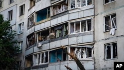 A man looks out of the balcony of his home, which was damaged after Russian bombardment at a residential neighborhood in Kharkiv, Ukraine, July 7, 2022.