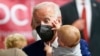 Prezidan Joe Biden kenbe yon ti bebe pandan lap vizite yon klinik kap bay vaksen COVID-19 nan legliz Sent Kominyon, nan Washington, Madi 21 Jyen 2022. 