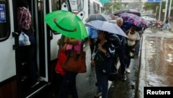 Fotografía de archivo, tomada en agosto del año pasado en Caracas, que muestra a usuarios del transporte público en Caracas durante un chubasco por la tormenta Bonnie.