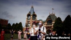 Sejumlah pengunjung Shanghai Disney Resort tampak mengenakan masker ketika berkunjung ke taman hiburan tersebut pada 30 Juni 2022. Taman hiburan itu mulai dibuka kembali untuk pengunjung setelah ditutup akibat penyebaran COVID-19 di Shanghai, China. (Foto: Reuters/Aly Song)