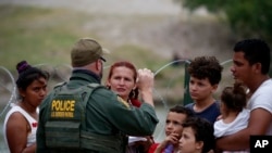 Un agente de la Patrulla Fronteriza de Estados Unidos conversa con un grupo de migrantes el 22 de mayo en el paso del Río Grande en Texas. EEUU ha expulsado del territorio más de 1.9 millones de veces a migrantes irregulares bajo la regla del Título 42. (Foto AP / Archivo)