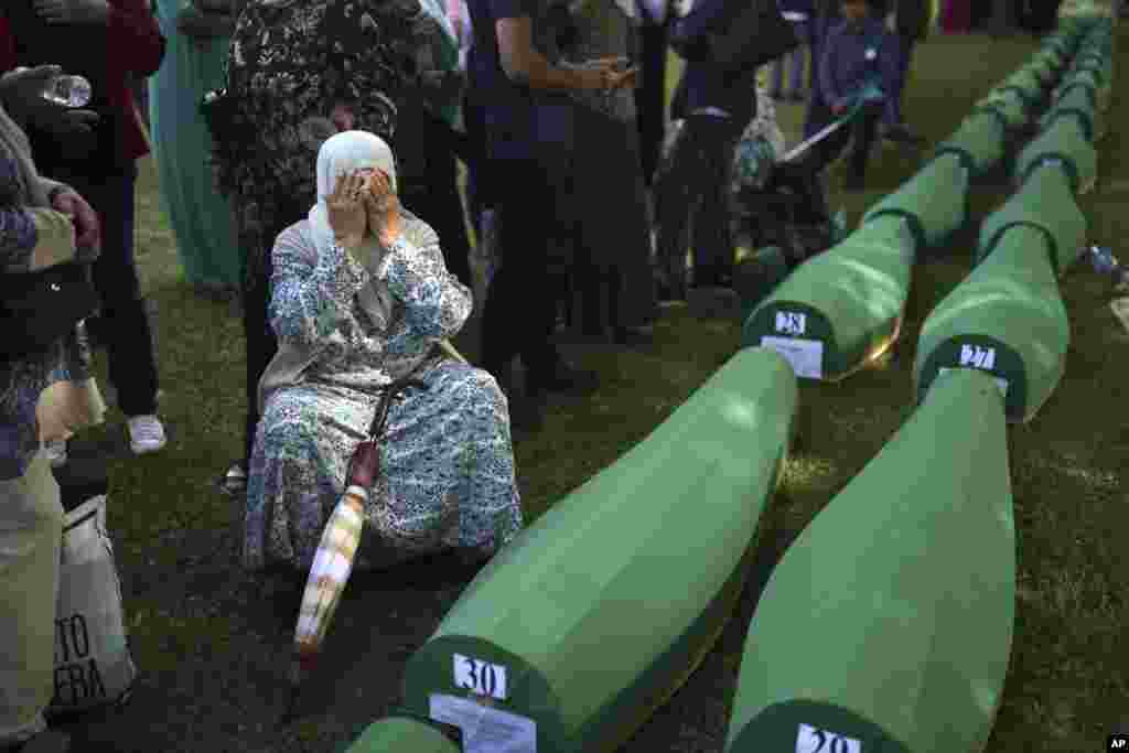 A Bosnian Muslim woman Bahta Aljic mourns next to the coffin containing remains of her husband who is among 50 newly identified victims of Srebrenica Genocide in Potocari, Bosnia-Herzegovina.