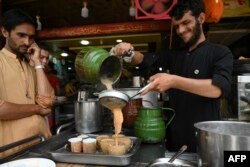 Seorang karyawan menuangkan teh untuk pelanggan di sebuah restoran di Islamabad, 15 Juni 2022. (Foto: Aamir QURESHI / AFP)