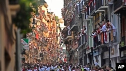 Gente corriendo por la calle por delante de los toros bravos en el primer día de encierros en las fiestas de San Fermín, Pamplona, en el norte de España, el jueves 7 de julio de 2022. (AP Foto/Álvaro Barrientos)
