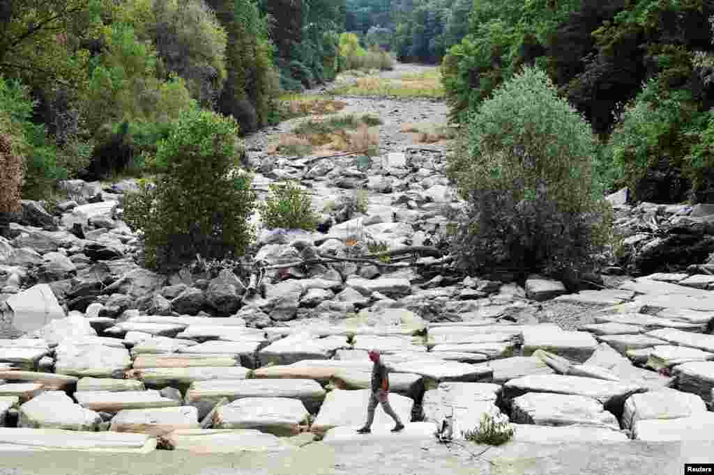 A man walks on the dry riverbed of Sangone river, a tributary of the Po river, which experiences its worst drought for 70 years, in Beinasco, Turin, Italy.