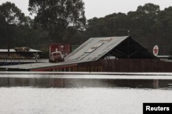 Tanda "tingkat ketinggian air" dari banjir yang sebelumnya, terlihat sebagian terendam di sisi bangunan, menyusul hujan lebat di pinggiran Londonderry di Sydney, Australia, 5 Juli 2022. REUTERS/Loren Elliott