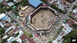 In this image taken from video, spectators gather around the wooden stands that collapsed during a bullfight in El Espinal, Tolima state, Colombia, Sunday, June 26, 2022. According to authorities, the collapse sent spectators plunging to the ground, killing at least four.