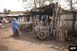 Seorang perempuan berjalan melewati bengkel sepeda di sebuah pasar di Bamako, 1 Februari 2022. (Foto: FLOREN VERGNES / AFP)