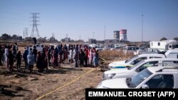 Les résidents du quartier informel de Nomzamo réagissent à une scène de crime où 14 personnes ont été abattues dans une taverne à Soweto le 10 juillet 2022.