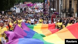 Para peserta pawai membentangkan bendera pelangi dalam pawai Pride 2022 di Kota London, Inggris, untuk memperingatai kesetaraan kaum LGBTQ+, Sabtu, 22 Juli 2022. (Foto: Henry Nicholls/Reuters)