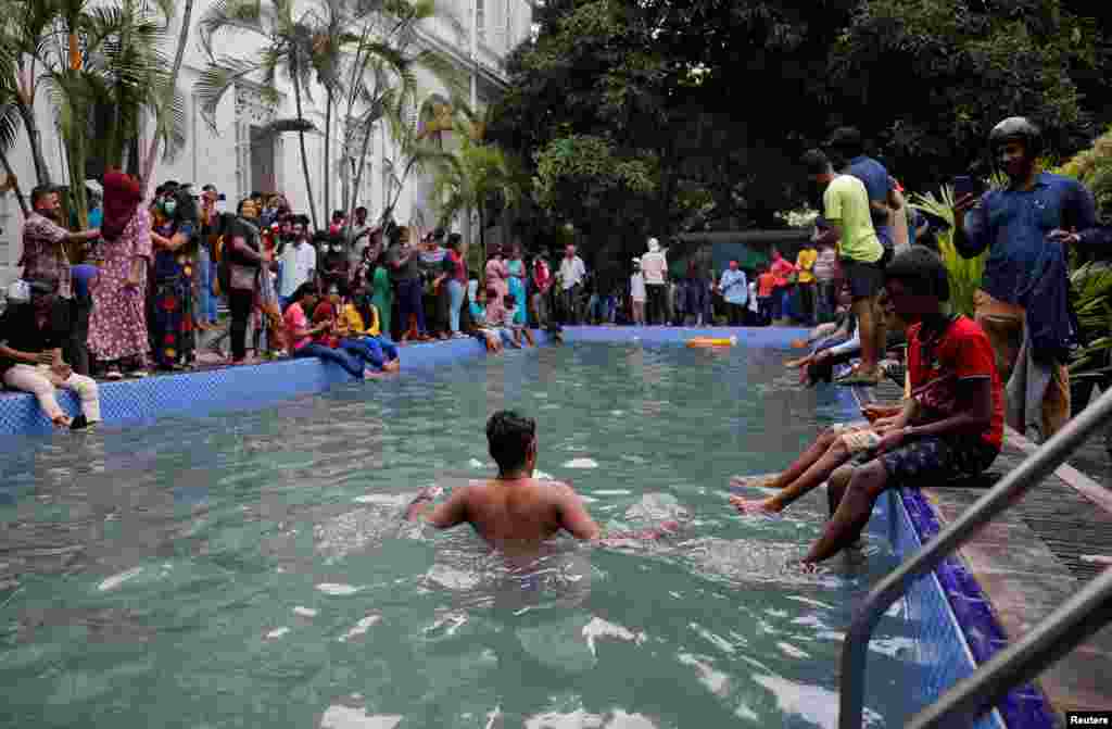 Un hombre se baña en la piscina mientras personas toman la casa del presidente el día después de que los manifestantes ingresaran al edificio.