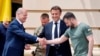 German Chancellor Olaf Scholz, left, shakes hands with in Kyiv with Ukrainian President Volodymyr Zelenskyy. In the center is French President Emmanuel Macron. 6.16.2022.