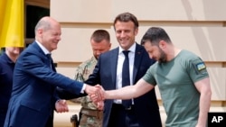 Kanselir Jerman Olaf Scholz, kiri, berjabat tangan dengan Presiden Ukraina Volodymyr Zelenskyy. (Ludovic Marin via AP)