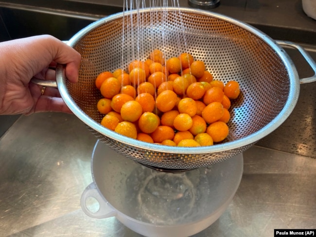 Kumquats are rinsed in a colander and the water is collected. It will be used to water plants, June 30, 2022, (AP Photo/Paula Munoz)