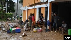 Des personnes se tiennent devant leurs maisons inondées à Bingerville, près d'Abidjan, le 21 juin 2022.
