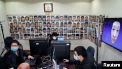 Des informaticiens chinois travaillent sur un logiciel de reconnaissance faciale qui identifie les individus même lorsqu'ils portent un masque facial, le 6 mars 2020.