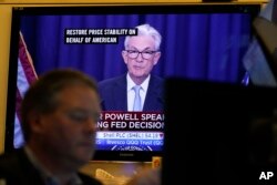 FILE - A news conference with Federal Reserve Chairman Jerome Powell is displayed on televisions while traders work on the floor at the New York Stock Exchange in New York, June 15, 2022.