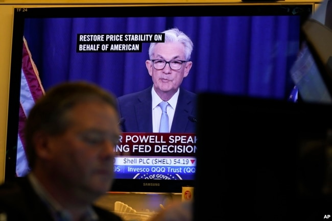 FILE - A news conference with Federal Reserve Chairman Jerome Powell is displayed on televisions while traders work on the floor at the New York Stock Exchange in New York, June 15, 2022.