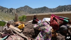 Anak-anak Afghanistan duduk di antara barang-barang mereka yang diselamatkan setelah gempa bumi di desa Gayan, di provinsi Paktika, Afghanistan, Jumat 24 Juni 2022. (Foto: AP)