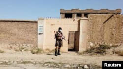 FILE - A Taliban fighter stands guard in front of a house adjacent to a suspected Islamic State hideout raided by Taliban forces, in northern Kabul, Afghanistan, Oct. 4, 2021.